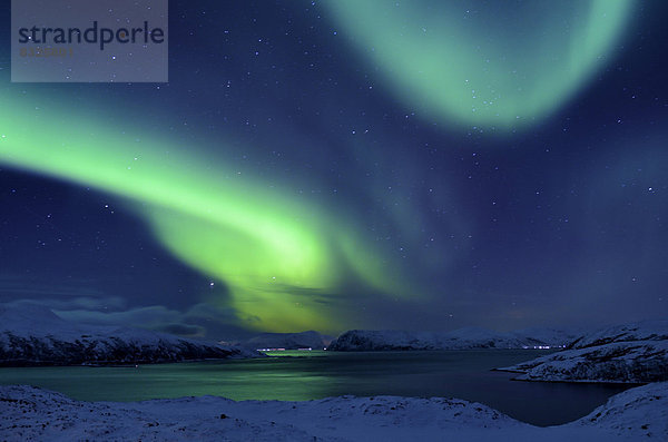 Polarlicht über Fjord in winterlicher Landschaft