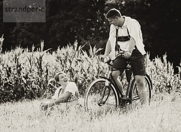 Mann und Frau in Tracht mit einem alten Fahrrad in der Natur