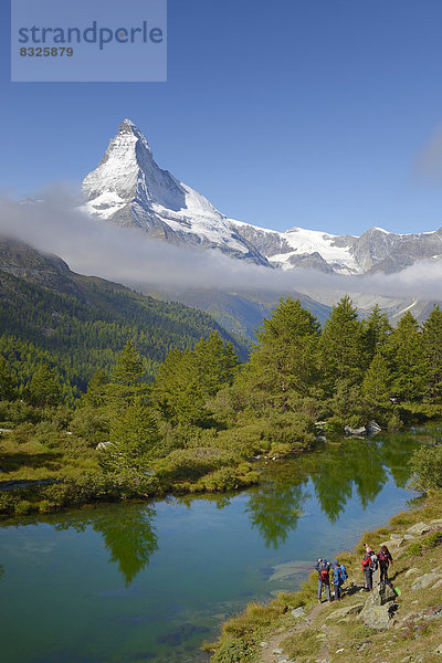 Wanderer fotografieren das Matterhorn mit dem Grindjisee im Vordergrund