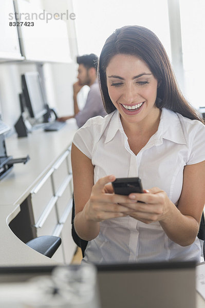 Woman text messaging in office  man in background
