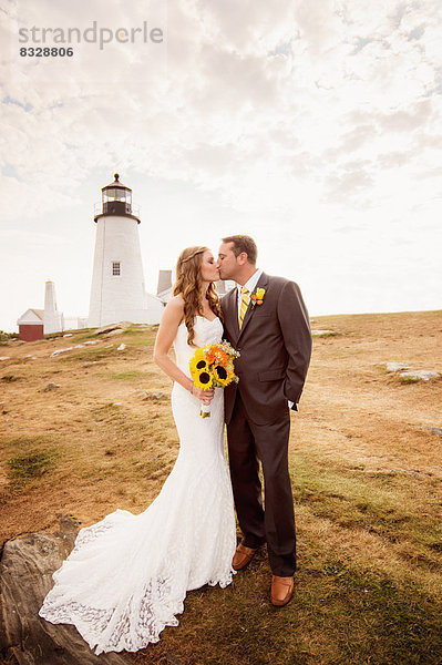 Portrait of married couple kissing  lighthouse in background