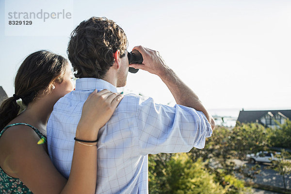 Rear view of couple  man looking through binoculars