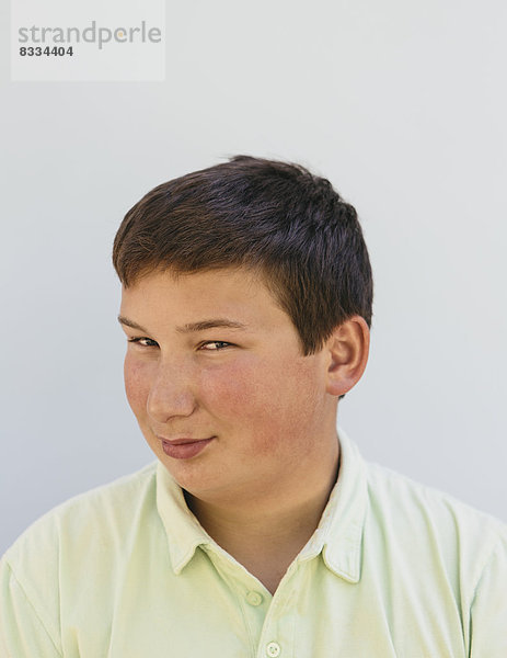 Porträt eines Teenagers mit kurzen schwarzen Haaren  der in die Kamera schaut und lächelt.