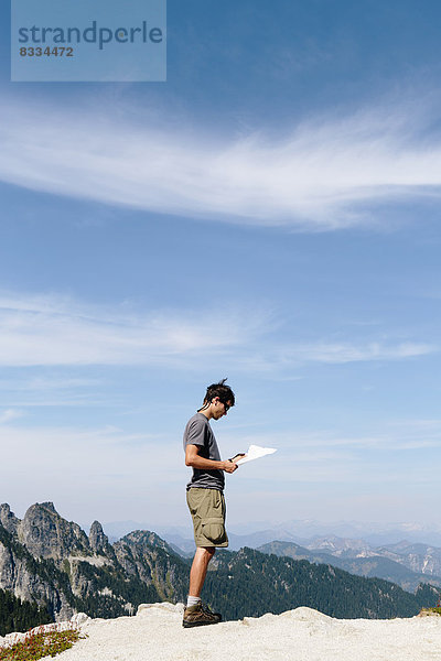 Ein Wanderer auf dem Berggipfel  der auf eine Karte schaut. Überraschungsberg  Alpine Lakes Wilderness  im Mount Baker-Snoqualmie National Forest