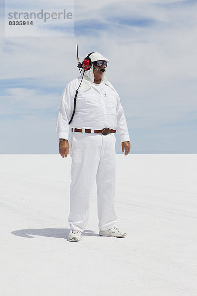 Ein Mann in weißem Overall  mit einem Funkkopfhörer  ein offizieller Zeitnehmer bei einer Autorennen-Veranstaltung  Speed Week.