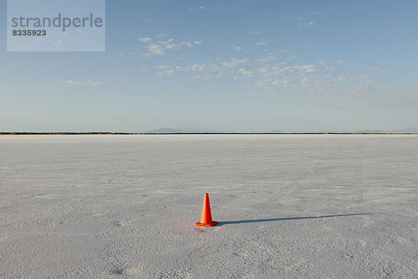 Ein einsamer Verkehrskegel auf der weißen  reflektierenden  mineralisch bestäubten Oberfläche der Bonneville Salt Flats im frühen Morgenlicht.