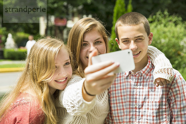 Drei junge Leute  zwei Mädchen und ein Junge  posieren und fotografieren sich selbst.