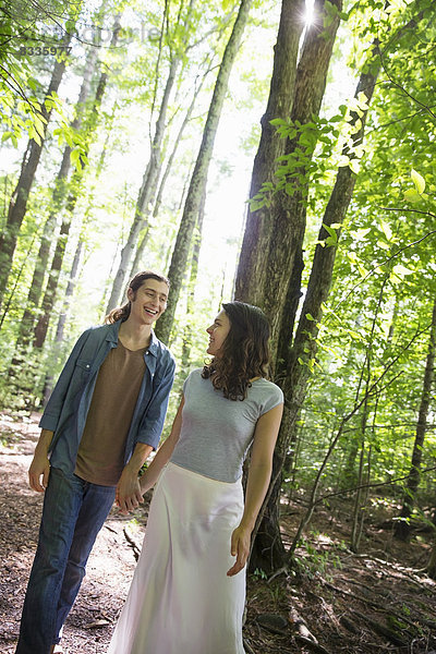 Zwei Menschen  eine junge Frau und ein Mann  gehen Seite an Seite im Wald spazieren.