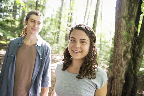 Zwei Menschen  eine junge Frau und ein Mann  gehen Seite an Seite im Wald spazieren.