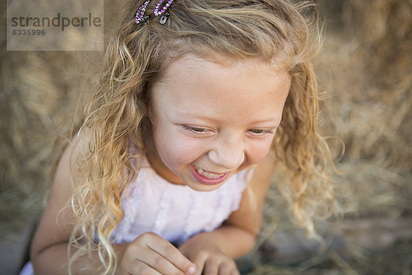 Ein junges Mädchen in einer Scheune beim Lachen.