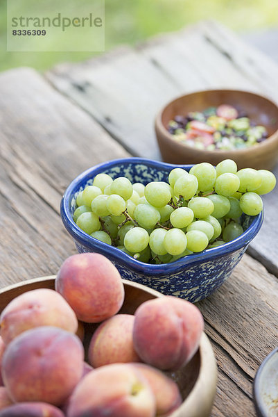 Ein gedeckter Gartentisch mit einem Buffet mit Salat  frischem Gemüse und Obst.