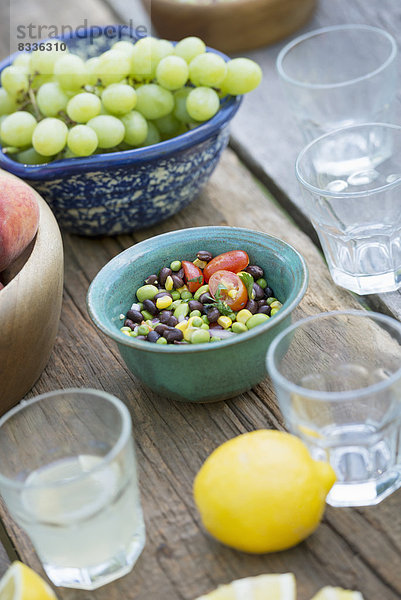 Ein gedeckter Gartentisch mit einem Buffet mit Salat  frischem Gemüse und Obst.