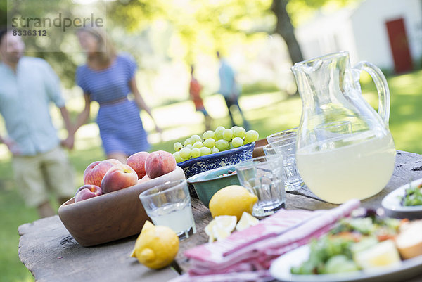 Ein sommerliches Buffet mit Obst und Gemüse  das auf einem Tisch aufgebaut ist. Menschen im Hintergrund.