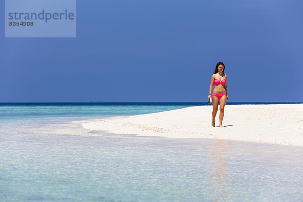 Frau geht mit einem Buch am Strand entlang  Malé  Nord-Malé-Atoll  Malediven