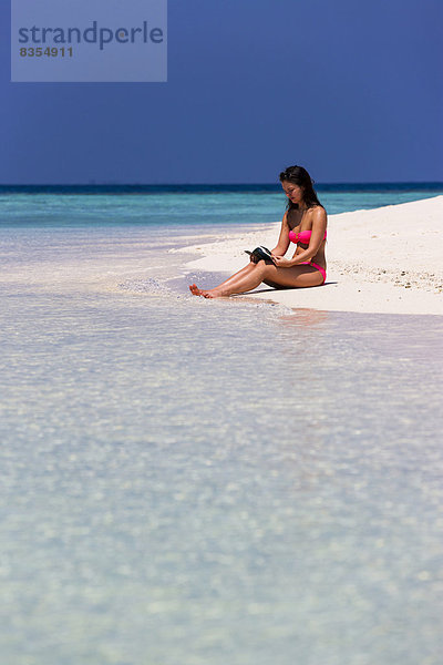Frau sitzt mit einem Buch am Strand  Malé  Nord-Malé-Atoll  Malediven