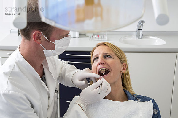 Frau beim Zahnarzt  Zahnarzt kontrolliert die Zähne  Deutschland