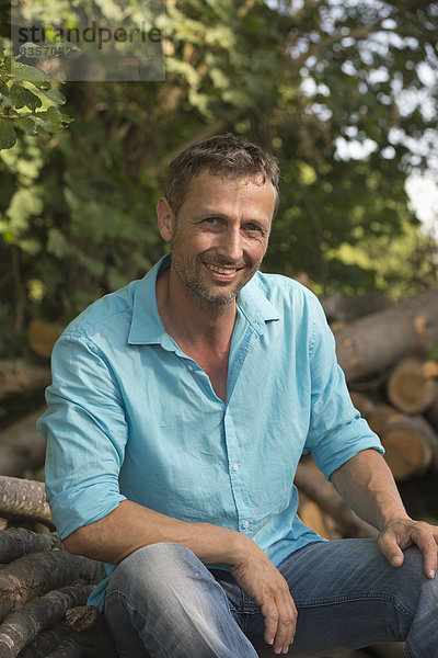 Lächelnder Mann beim Holzhaufen