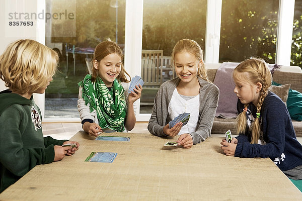 Vier Kinder spielen Kartenspiel im Wohnzimmer