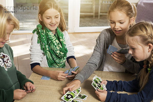 Vier Kinder spielen Kartenspiel im Wohnzimmer