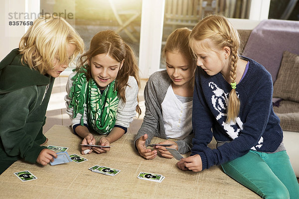 Vier Kinder spielen Kartenspiel im Wohnzimmer