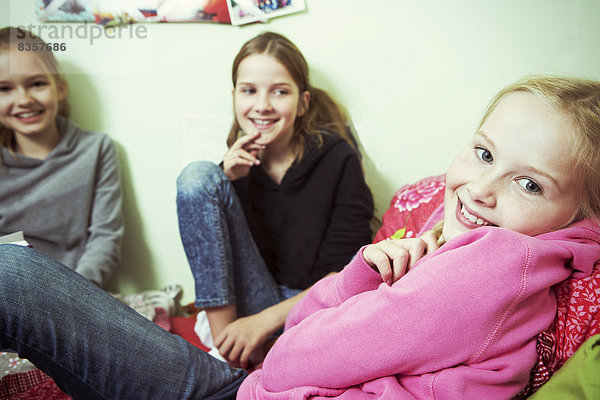 Drei lächelnde Mädchen im Bett