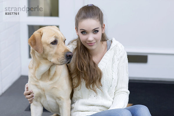 Teenagermädchen mit Hund vor einer Haustür sitzend
