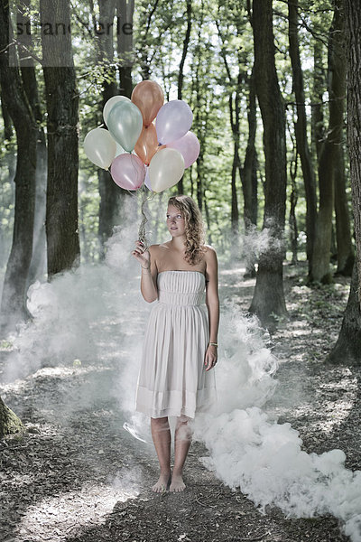 Junge Frau in weißem Kleid mit Luftballons