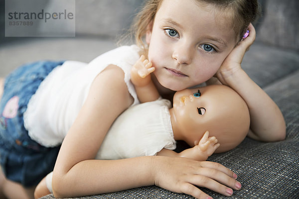 Porträt eines kleinen Mädchens auf dem Sofa mit ihrer Puppe  Nahaufnahme