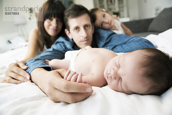 Junge Eltern mit kleiner Tochter und neugeborenem Sohn zu Hause