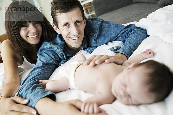 Glückliche junge Eltern mit ihrem neugeborenen Sohn zu Hause