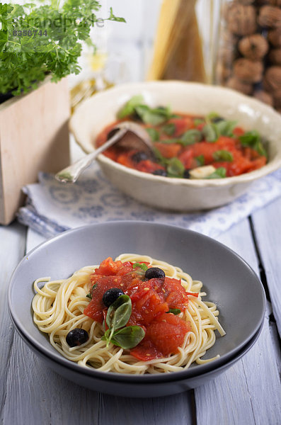 Spaghetti mit Sauce aus gegrillten Tomaten mit schwarzen Oliven und Basilikumblättern  Studioaufnahme