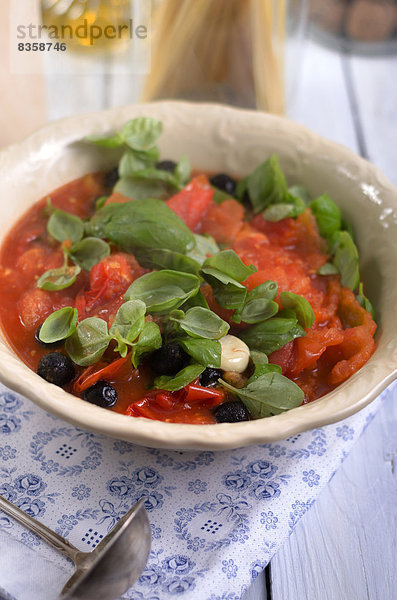 Sauce aus gegrillten Tomaten mit schwarzen Oliven und Basilikumblättern  Studioaufnahme