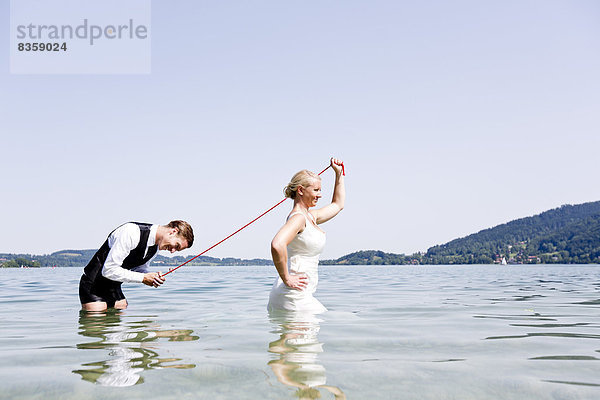 Deutschland  Bayern  Tegernsee  Hochzeitspaar im See stehend  Brautpaar mit Bräutigam an der Leine