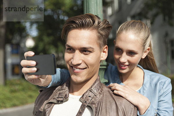 Young couple taking a picture of themselves with a smart phone