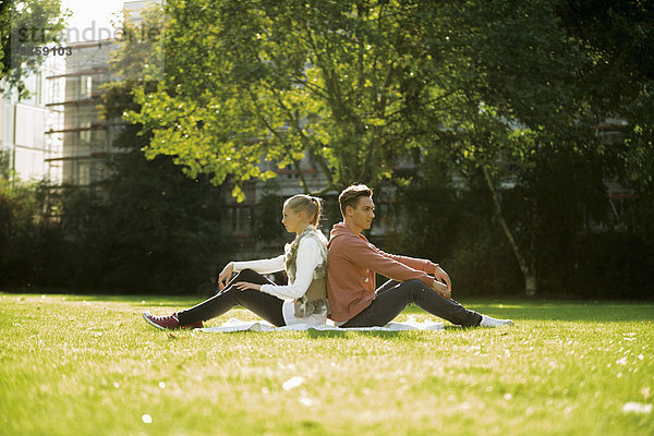 Young couple sitting back to back on a meadow