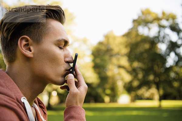 Junger Mann küsst sein Smartphone  Nahaufnahme