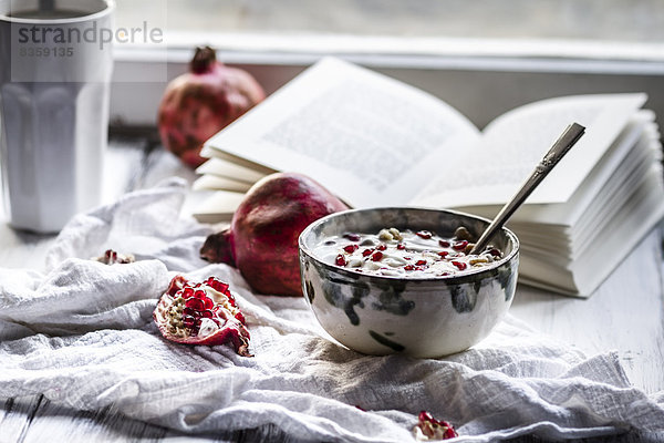 Healthy breakfast with pomegranate in yogurt  Coffee and opened book