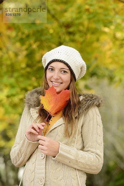 Lächelnde junge Frau mit Herbstblatt  Portrait