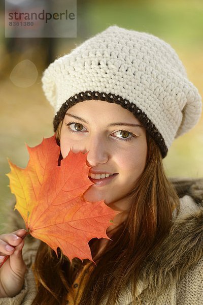 Lächelnde junge Frau mit Herbstblatt  Portrait