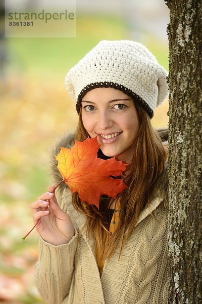 Lächelnde junge Frau mit Herbstblatt  Portrait