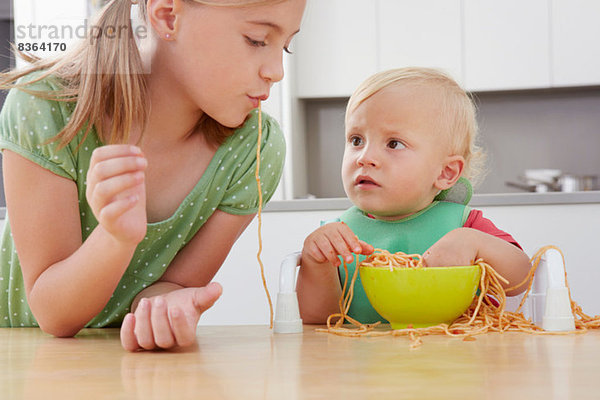 Mädchen und Kleinkind beim Spielen mit Spaghetti