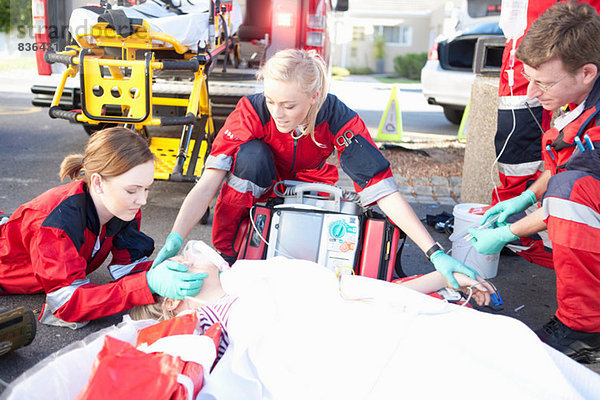 Drei Sanitäter mit Patient auf der Trage mit Sauerstoffmaske