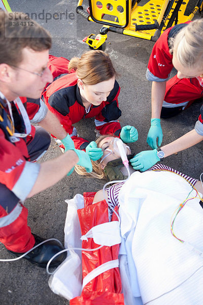 Drei Sanitäter mit Patient auf der Trage mit Sauerstoffmaske