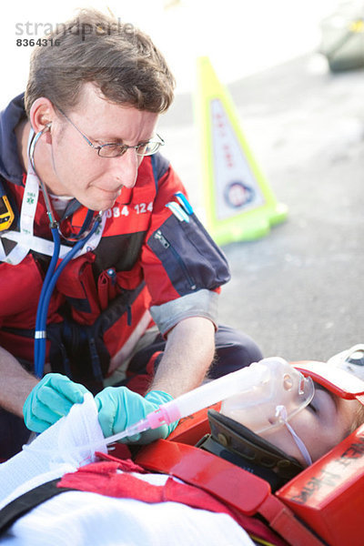 Rettungssanitäter mit Stethoskop  Patient auf Trage mit Sauerstoffmaske