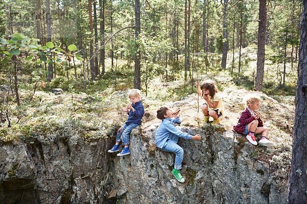 Kinder sitzen auf Felsen im Wald und essen Picknick