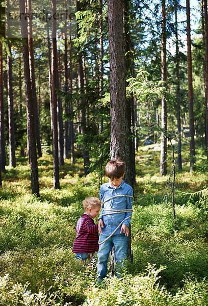 Mädchen bindet Bruder an Baum