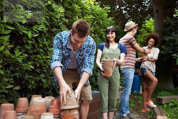 Vier Freunde beim Stapeln von Terrakotta-Pflanzentöpfen