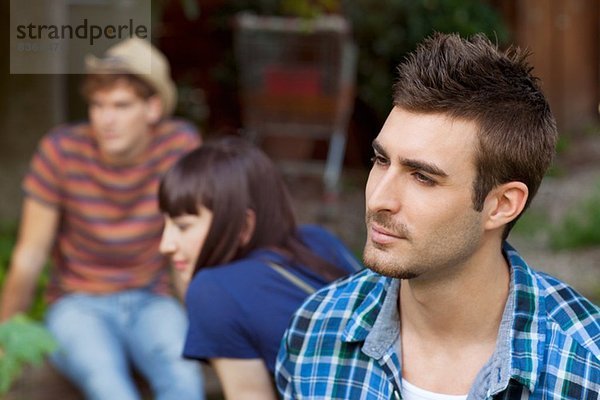 Porträt eines jungen Mannes mit Freunden im Hintergrund