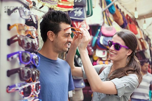 Junges Paar probiert eine Sonnenbrille an  Markt in San Lorenzo  Florenz  Toskana  Italien