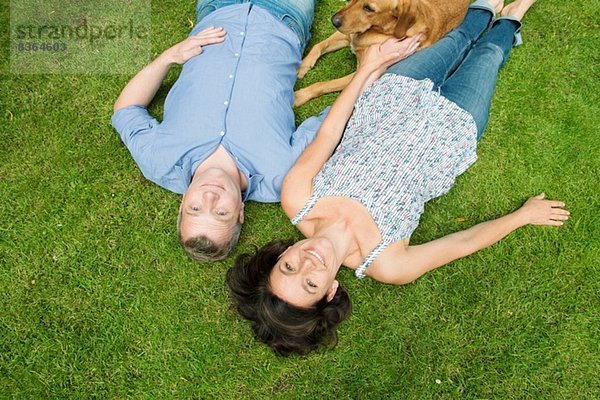 Porträt eines erwachsenen Paares auf Gras mit Hund